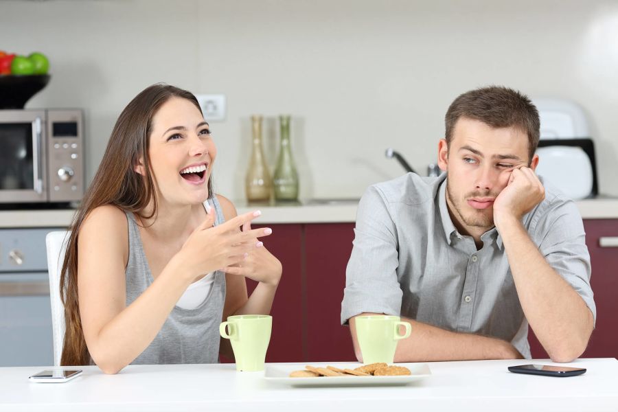 Mann sitzt gelangweilt mit Frau am Tisch